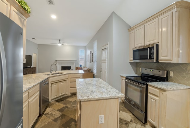 kitchen with a center island, backsplash, sink, ceiling fan, and appliances with stainless steel finishes