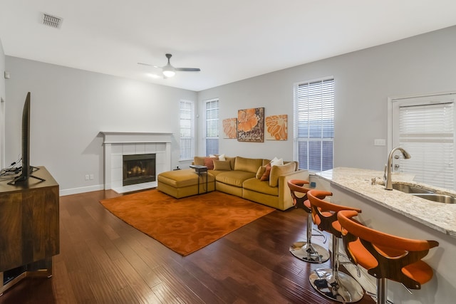 living room featuring a fireplace, dark hardwood / wood-style floors, ceiling fan, and sink