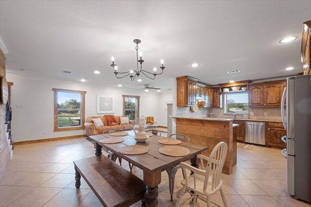 tiled dining room featuring ornamental molding, ceiling fan with notable chandelier, and plenty of natural light