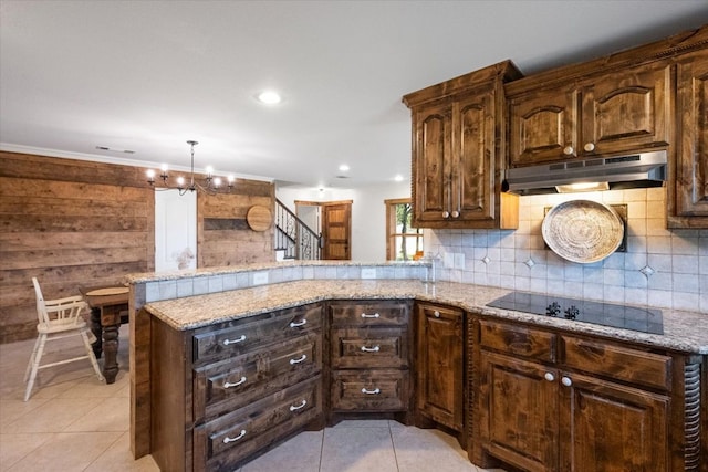 kitchen featuring a notable chandelier, kitchen peninsula, decorative light fixtures, and black electric cooktop