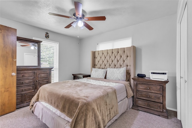 carpeted bedroom featuring ceiling fan and a textured ceiling