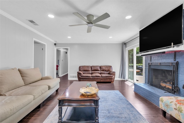 living room with a brick fireplace, ornamental molding, dark hardwood / wood-style flooring, and ceiling fan