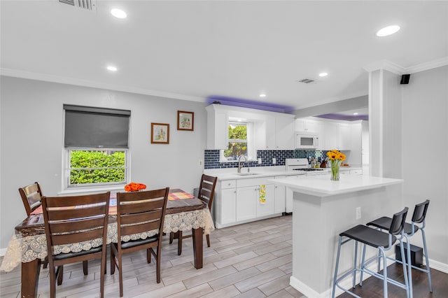 kitchen featuring light wood-type flooring, white appliances, crown molding, kitchen peninsula, and white cabinetry