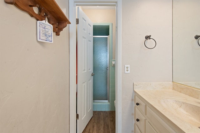 bathroom with hardwood / wood-style floors, a shower with shower door, and vanity