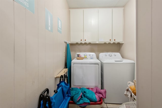 washroom with wood walls, cabinets, light tile patterned floors, and washer and clothes dryer