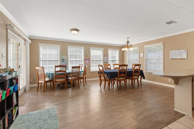 dining space featuring ornamental molding, a textured ceiling, hardwood / wood-style floors, and a wealth of natural light