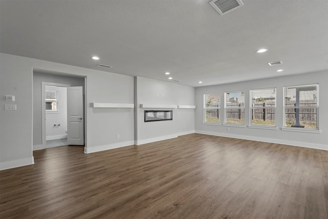 unfurnished living room featuring a textured ceiling and dark hardwood / wood-style floors