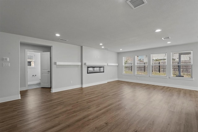 unfurnished living room with dark wood-type flooring and a textured ceiling