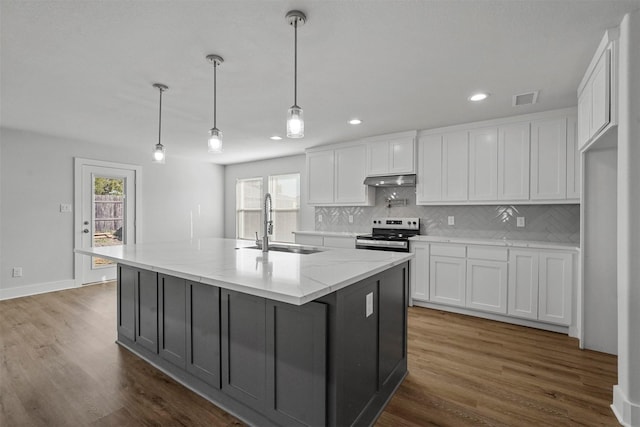 kitchen featuring electric stove, a center island with sink, and white cabinets