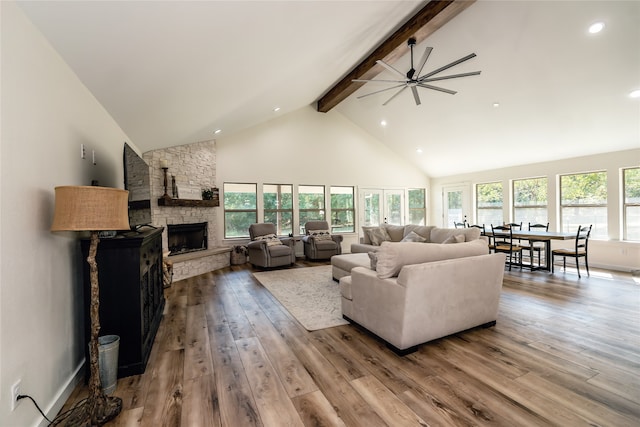 living room with beamed ceiling, a fireplace, ceiling fan, and light hardwood / wood-style floors