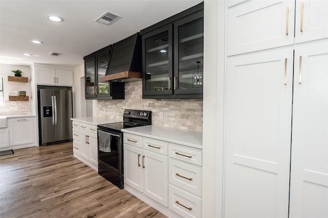 kitchen featuring stainless steel fridge, light hardwood / wood-style flooring, black range with electric stovetop, custom range hood, and white cabinets