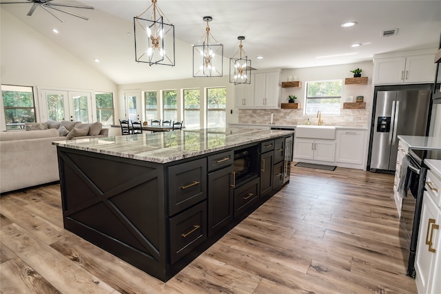 kitchen featuring light wood-type flooring, hanging light fixtures, white cabinets, black appliances, and a center island