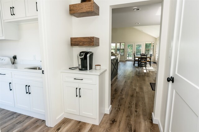 bar with white cabinets, lofted ceiling, and light hardwood / wood-style flooring