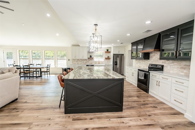 kitchen with custom range hood, stainless steel refrigerator with ice dispenser, backsplash, and electric range