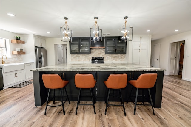 kitchen with a large island, light hardwood / wood-style floors, sink, and black appliances