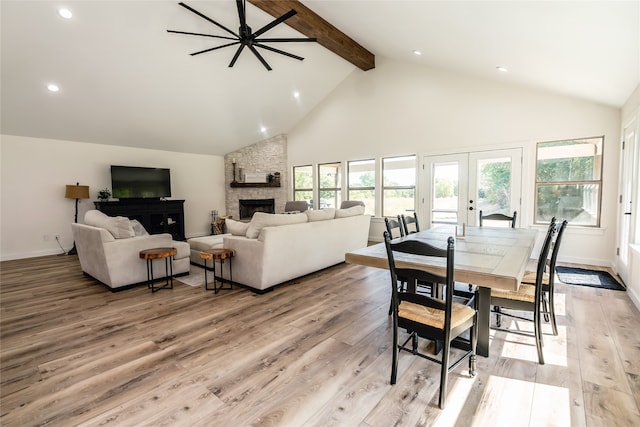 living room featuring ceiling fan, beamed ceiling, high vaulted ceiling, a fireplace, and light hardwood / wood-style floors