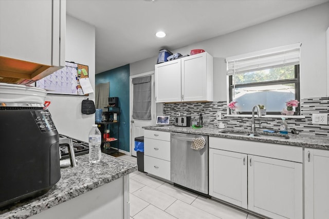 kitchen featuring white cabinets, decorative backsplash, stainless steel dishwasher, and a sink