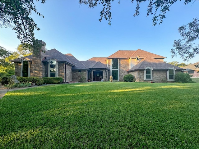 view of front of home with a front yard, stone siding, and a chimney