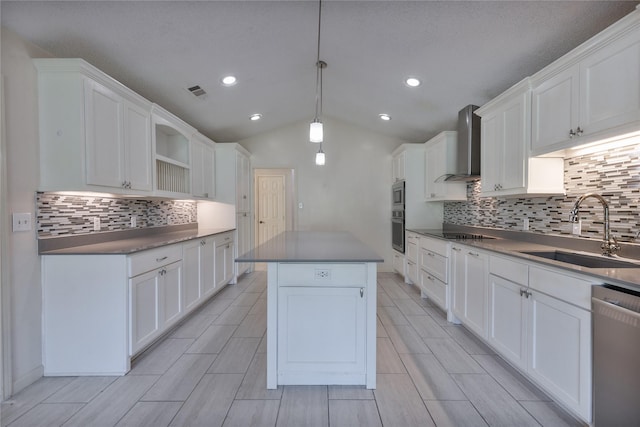 kitchen with dark countertops, wall chimney exhaust hood, a kitchen island, appliances with stainless steel finishes, and a sink