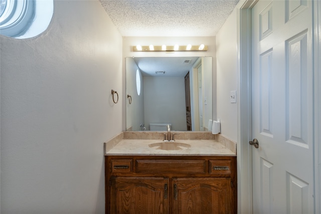 bathroom featuring vanity, toilet, and a textured ceiling