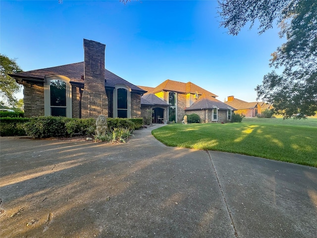 view of front of home with stone siding, a chimney, and a front lawn