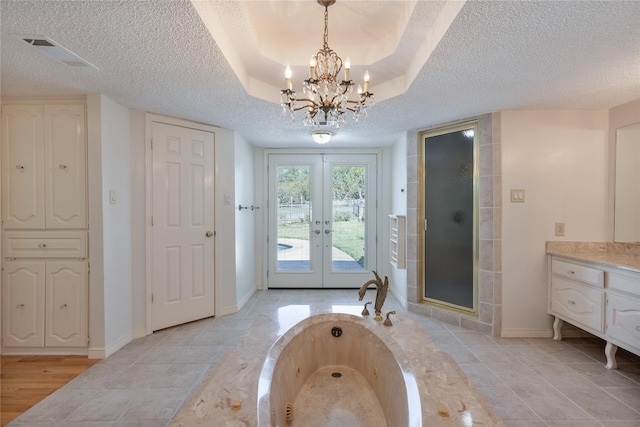 bathroom with a textured ceiling, vanity, visible vents, french doors, and a tray ceiling