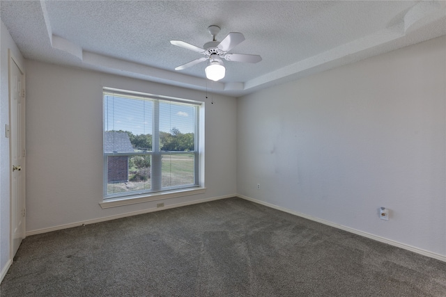 carpeted empty room with a textured ceiling, a tray ceiling, and ceiling fan