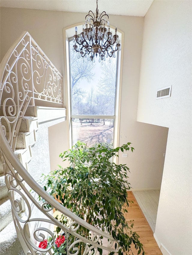 room details with baseboards, wood finished floors, visible vents, and a notable chandelier