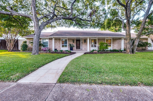 ranch-style house featuring brick siding, a front lawn, and covered porch