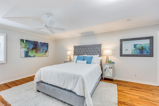 bedroom with ceiling fan, baseboards, crown molding, and wood finished floors
