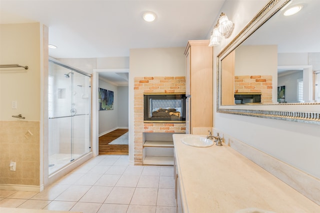 bathroom with a shower with door, a multi sided fireplace, vanity, and tile patterned flooring