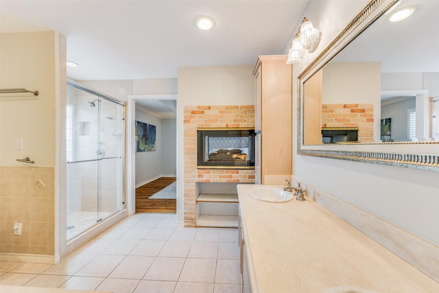 bathroom featuring a shower stall, tile patterned floors, a multi sided fireplace, vanity, and recessed lighting