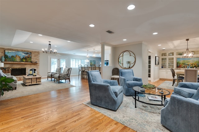 living room with built in features, a fireplace, light wood-type flooring, and crown molding