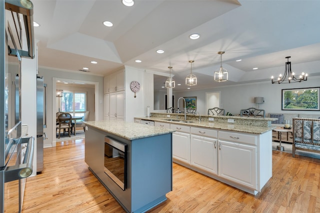 kitchen featuring a center island, a sink, a tray ceiling, white cabinetry, and appliances with stainless steel finishes