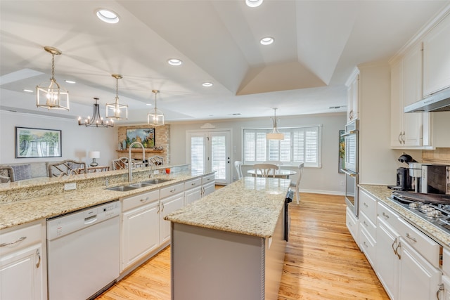 kitchen with appliances with stainless steel finishes, sink, a center island, white cabinetry, and vaulted ceiling