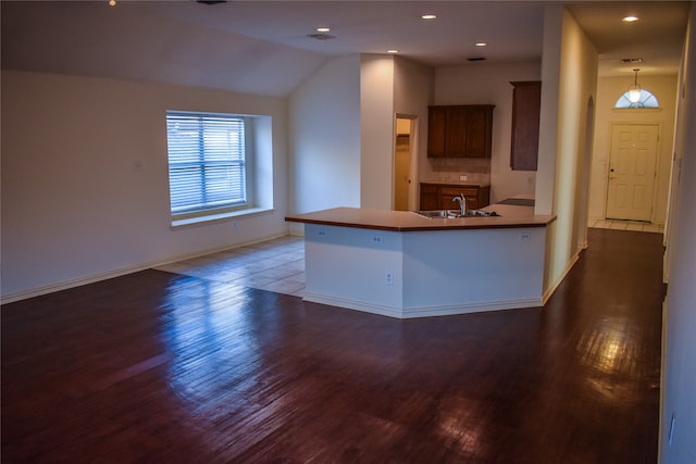 kitchen featuring hanging light fixtures, sink, kitchen peninsula, vaulted ceiling, and dark hardwood / wood-style flooring