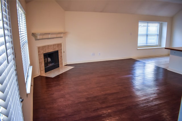 unfurnished living room featuring hardwood / wood-style flooring, lofted ceiling, and a tile fireplace