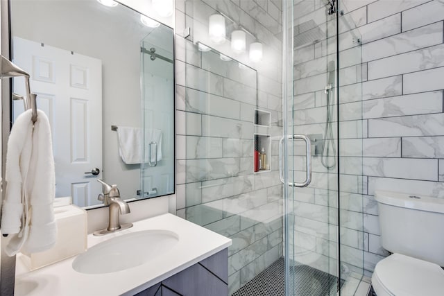 bathroom featuring toilet, a shower with door, and vanity