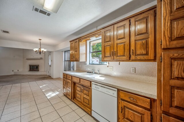 kitchen with pendant lighting, light tile patterned flooring, sink, dishwasher, and a fireplace