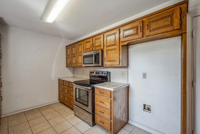 kitchen featuring a textured ceiling, stainless steel appliances, and light tile patterned floors