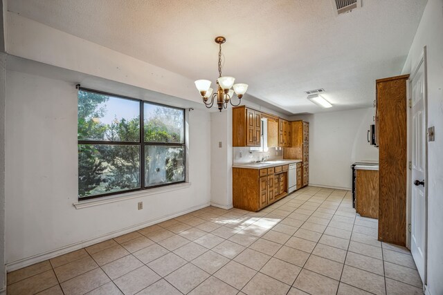 kitchen featuring light tile patterned floors, a notable chandelier, hanging light fixtures, and white dishwasher