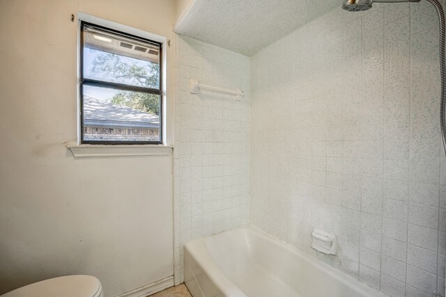 bathroom featuring toilet, tiled shower / bath, and a textured ceiling