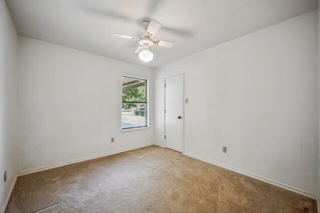 carpeted spare room featuring ceiling fan