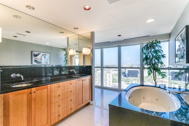 bathroom featuring tile patterned flooring, vanity, and tiled bath