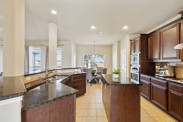 kitchen featuring dark stone counters, a center island, sink, and stainless steel appliances