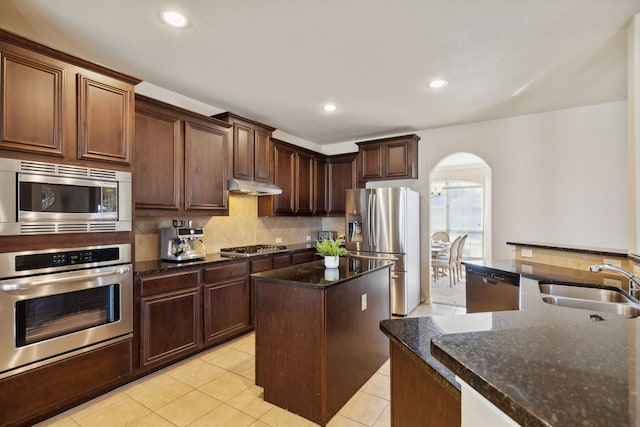 kitchen featuring dark stone countertops, stainless steel appliances, sink, and a kitchen island