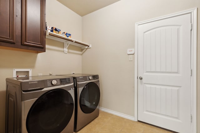 clothes washing area featuring washing machine and dryer, light tile patterned floors, and cabinets