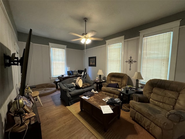 living room featuring light wood-type flooring, a textured ceiling, and ceiling fan