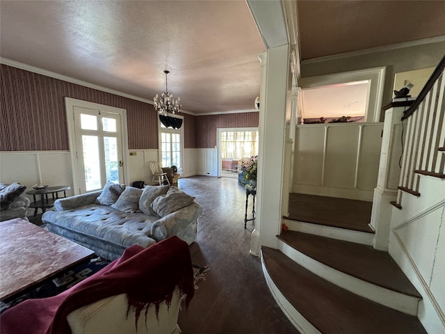 living room featuring hardwood / wood-style floors, a wealth of natural light, ornamental molding, and a notable chandelier