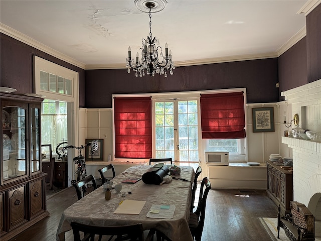 dining room with french doors, crown molding, a notable chandelier, dark hardwood / wood-style flooring, and a brick fireplace